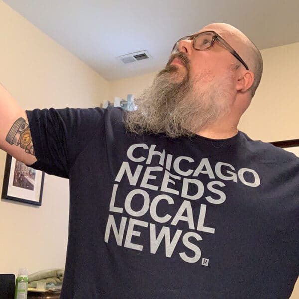 The author wearing a navy t-shirt that says "Chicago Needs Local News"