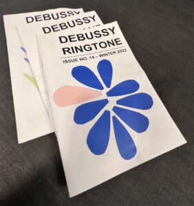 A stack of three issues of Debussy Ringtone. It's a plain white paper background with the title at the top and an abstract flower shape in the middle.