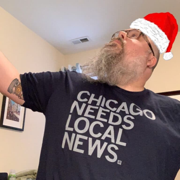 Your fearless author wearing a navy blue t-shirt with Chicago Needs Local News printed int grey, all caps. I'm also wearing a Santa hat.